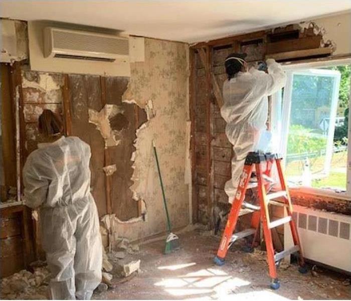 technician removing damaged insulation during water restoration