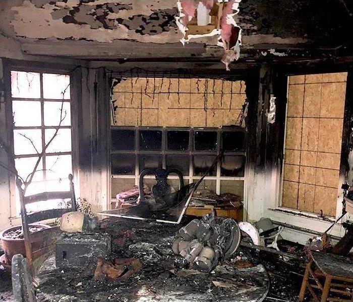 fire damaged living room with extensive structural and cosmetic damages
